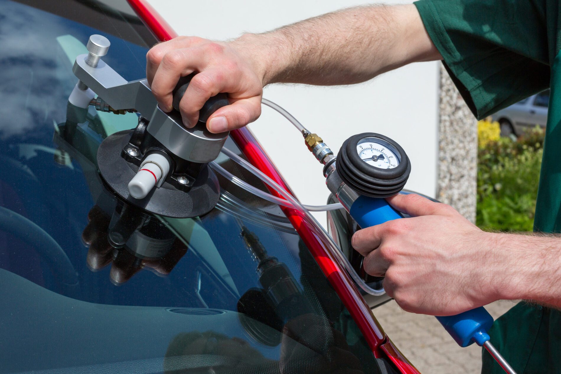 Glazier repairing windshield on a car after stone-chipping damage Glazier repairing windshield on a car after stone-chipping damage